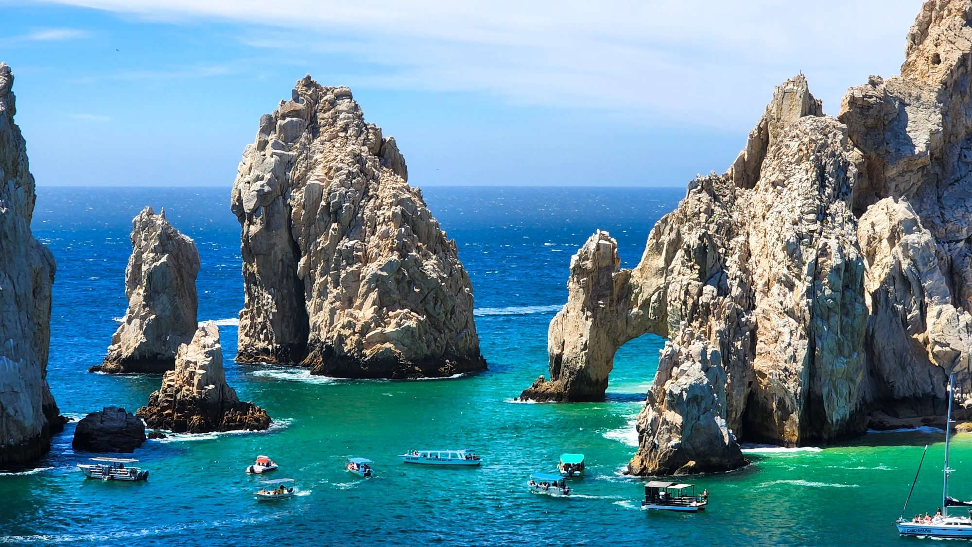 boats in the water near the arch at Land's End in Cabo
