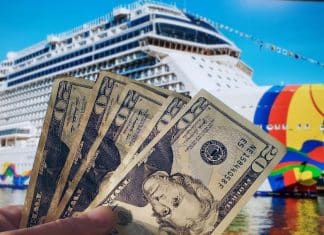 stack of 20 dollar bills in front of a norwegian cruise line cruise ship