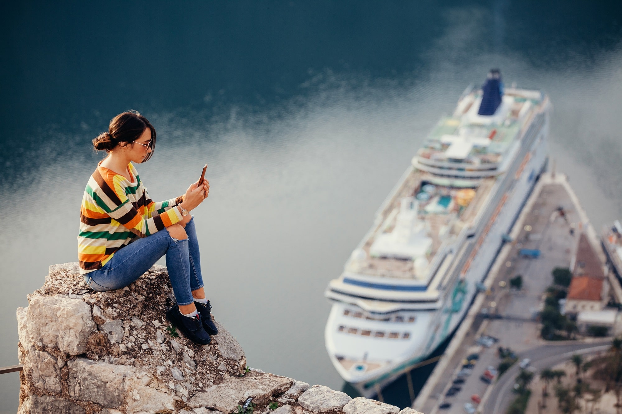 woman using cell phone near a cruise ship in port