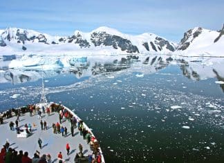 cruise ship in Antarctica with icebergs and mountains in the still water