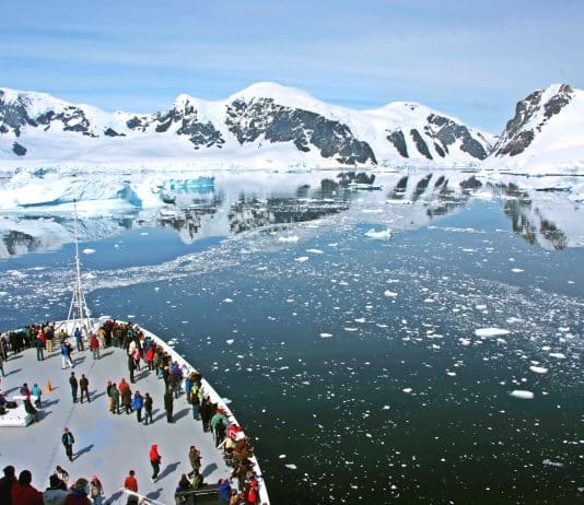 cruise ship in Antarctica with icebergs and mountains in the still water