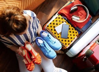 Woman holding shoes with suitcase getting ready for a trip