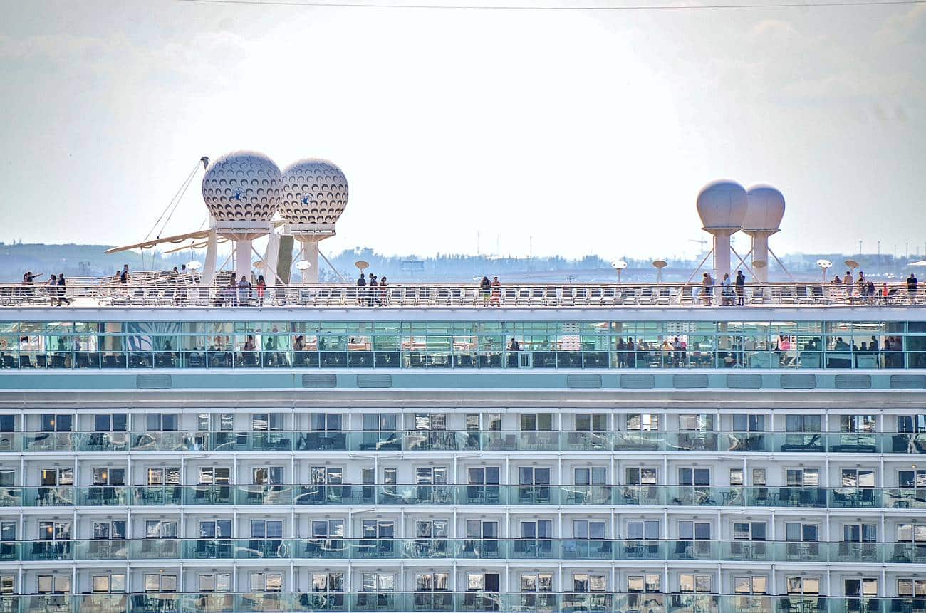 Image of cruise ship from side, top deck as it sails out of port