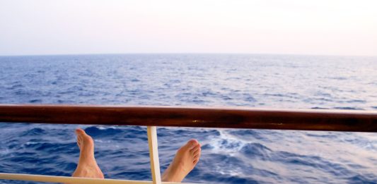 Man on cruise ship balcony relaxing