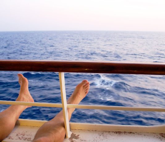 Man on cruise ship balcony relaxing