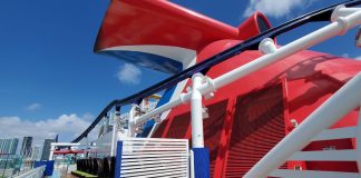 Carnival cruise line ship's whale tail on top deck with city in background